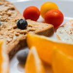 sliced bread with sliced orange and blue berries on white ceramic plate